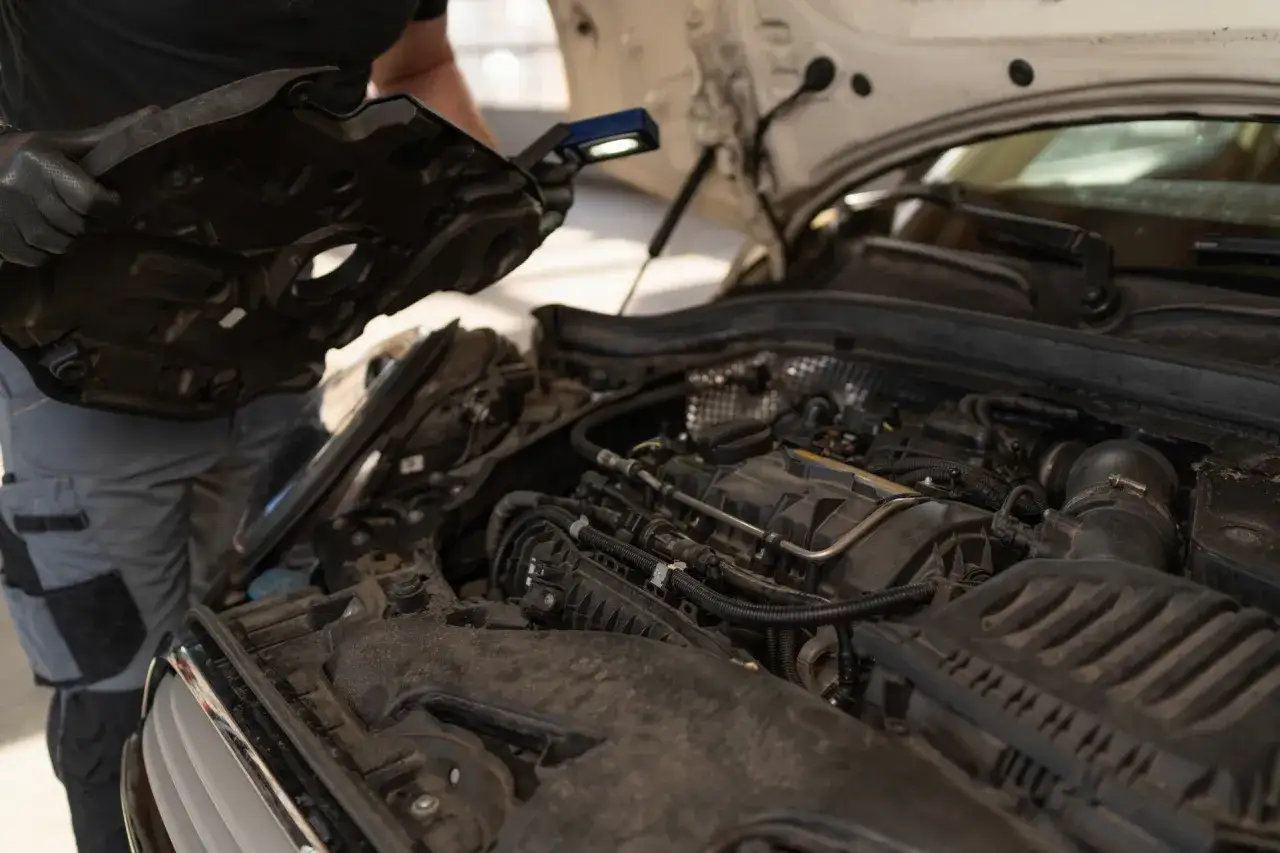 Mechanik sprawdza silnik, szukając objawów przegrzania. Widać elementy silnika i narzędzia.