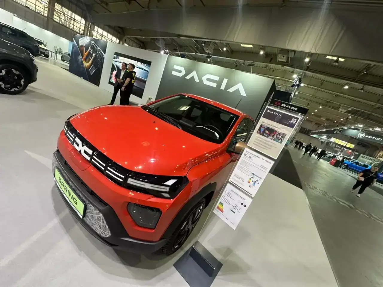 Czerwona Dacia Spring na targach motoryzacyjnych. Nowoczesny design i ekologiczne rozwiązania na rynku samochodowym.