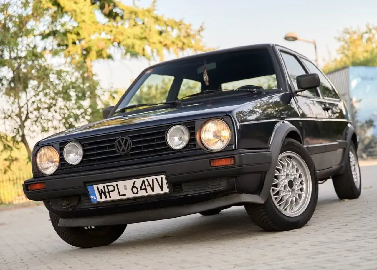 Klasyczny czarny VW Golf 2 z polskimi tablicami rejestracyjnymi WPL 64VV, zaparkowany na zewnątrz.