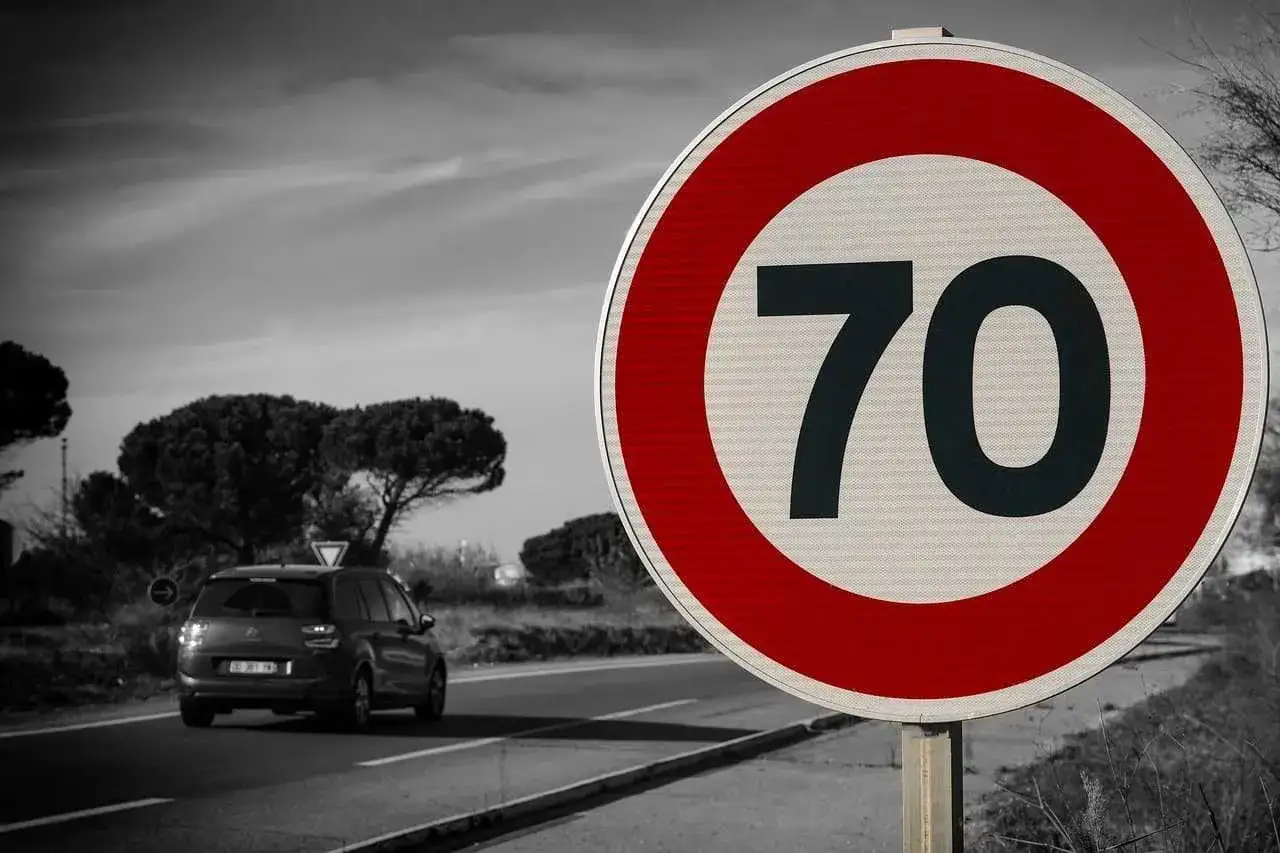 Znak ograniczenia prędkości do 70 km/h. Samochód jedzie drogą ekspresową, przestrzegając przepisów.