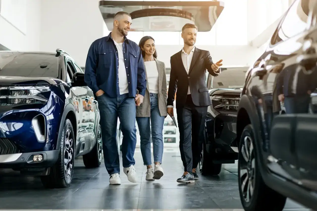 Para sprawdzająca auto w salonie, jak sprawdzić czy auto jest w leasingu. Sprzedawca pokazuje im nowe modele.