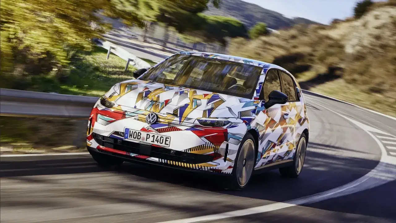 Nowy model Volkswagena w artystycznym kamuflażu pokonuje zakręt na górskiej drodze.
