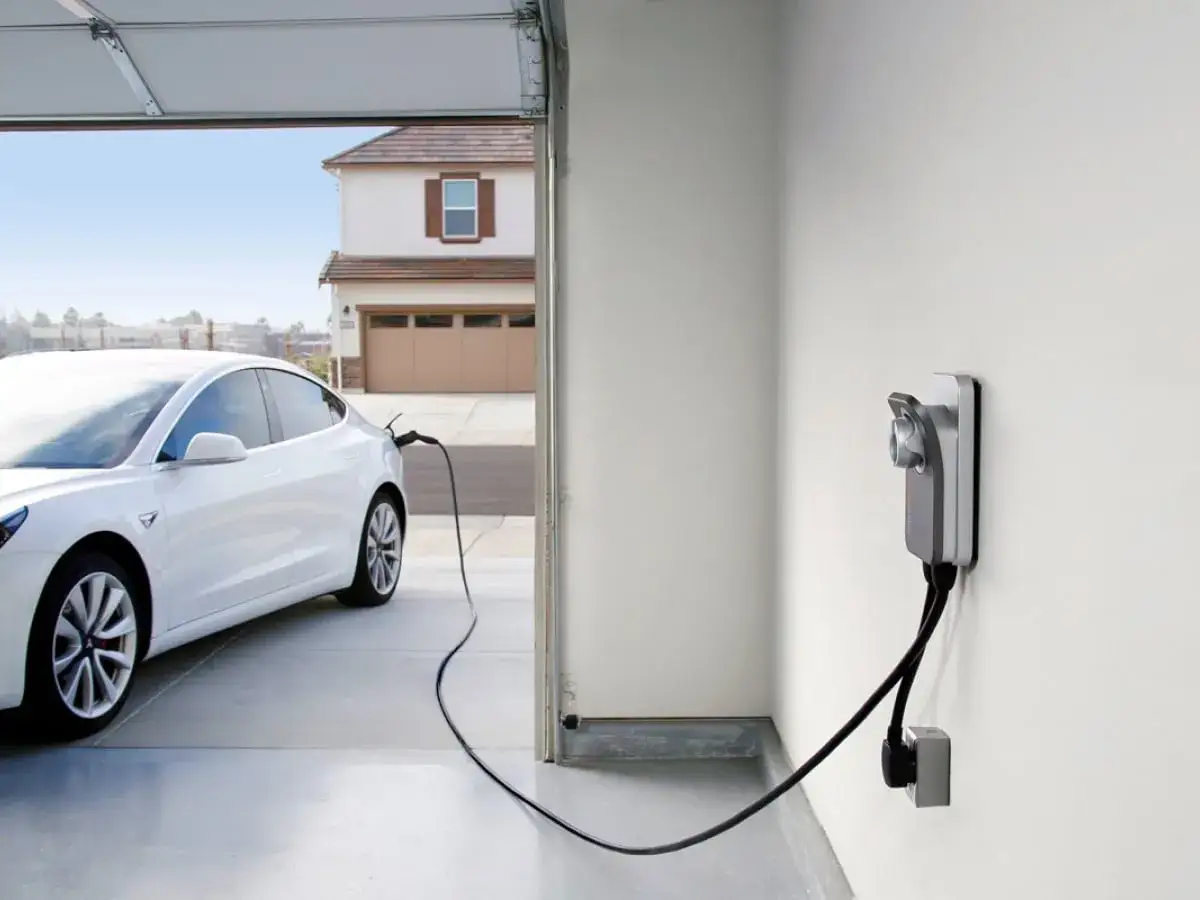 Biały samochód elektryczny ładuje się w garażu. To przyszłość motoryzacji, jaki samochód elektryczny wybrać?