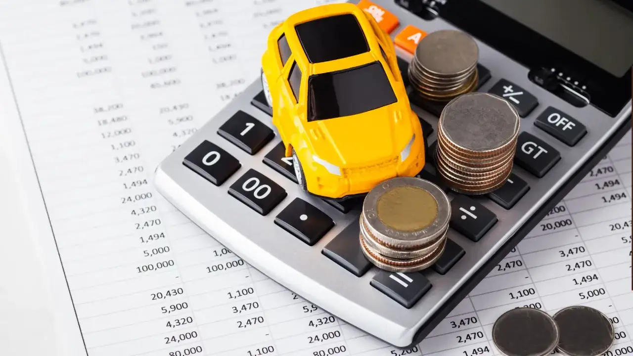 Żółty samochodzik na kalkulatorze ze stosami monet symbolizuje leasing bez wpłaty własnej. Finanse i marzenia o aucie.