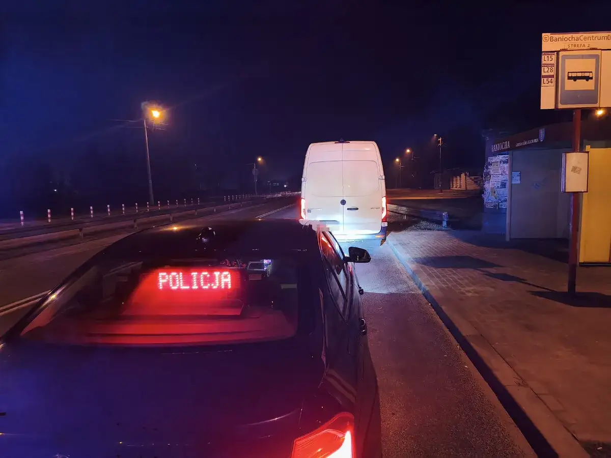 Nocna kontrola drogowa. Policja zatrzymała białą furgonetkę. Kierowca pewnie martwi się, kiedy zabierają prawo jazdy.
