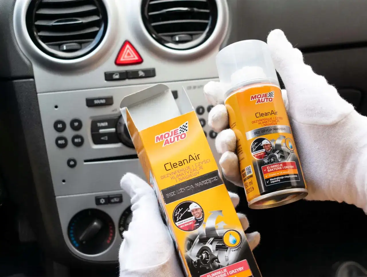 Ręce w białych rękawiczkach trzymają puszkę i pudełko preparatu Moje Auto CleanAir, który usuwa dziwny zapach w samochodzie, dezynfekując klimatyzację.