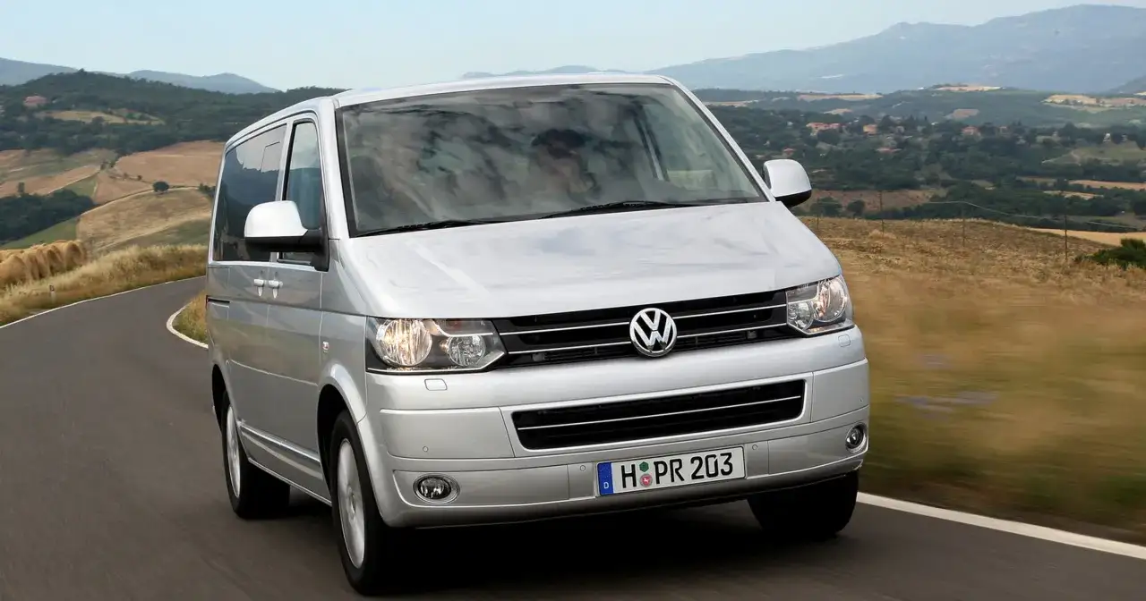 Srebrny Volkswagen Transporter na krętej drodze, idealny do akcje serwisowe vw. W tle malownicze wzgórza Toskanii.