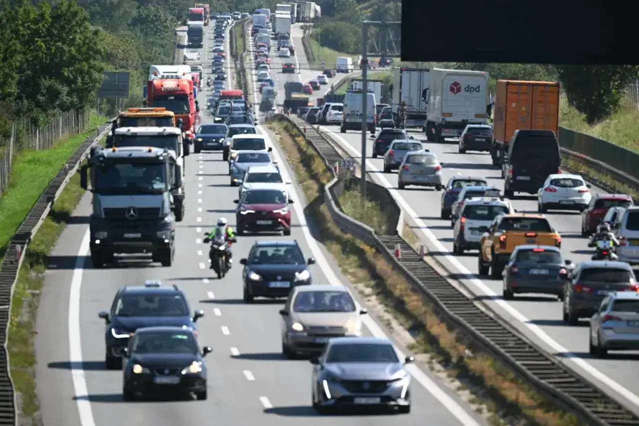 Korek na autostradzie, pokazujący dużą liczbę samochodów w Polsce. Widać ciężarówki, osobówki i motocykl.