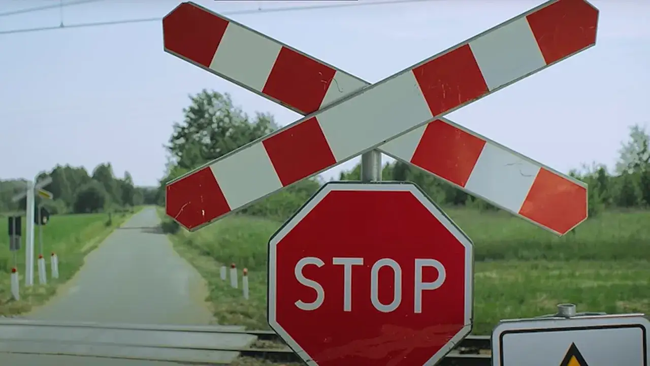 Przejazd kolejowy z rogatkami i znakiem STOP. Uważaj, by nie dostać mandatu za przejazd kolejowy.