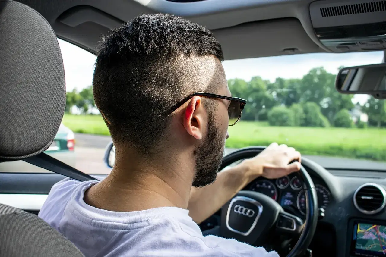 Mężczyzna w okularach prowadzi Audi. Zastanawia się, ile mam czasu na ubezpieczenie samochodu po zakupie, by móc legalnie jeździć.