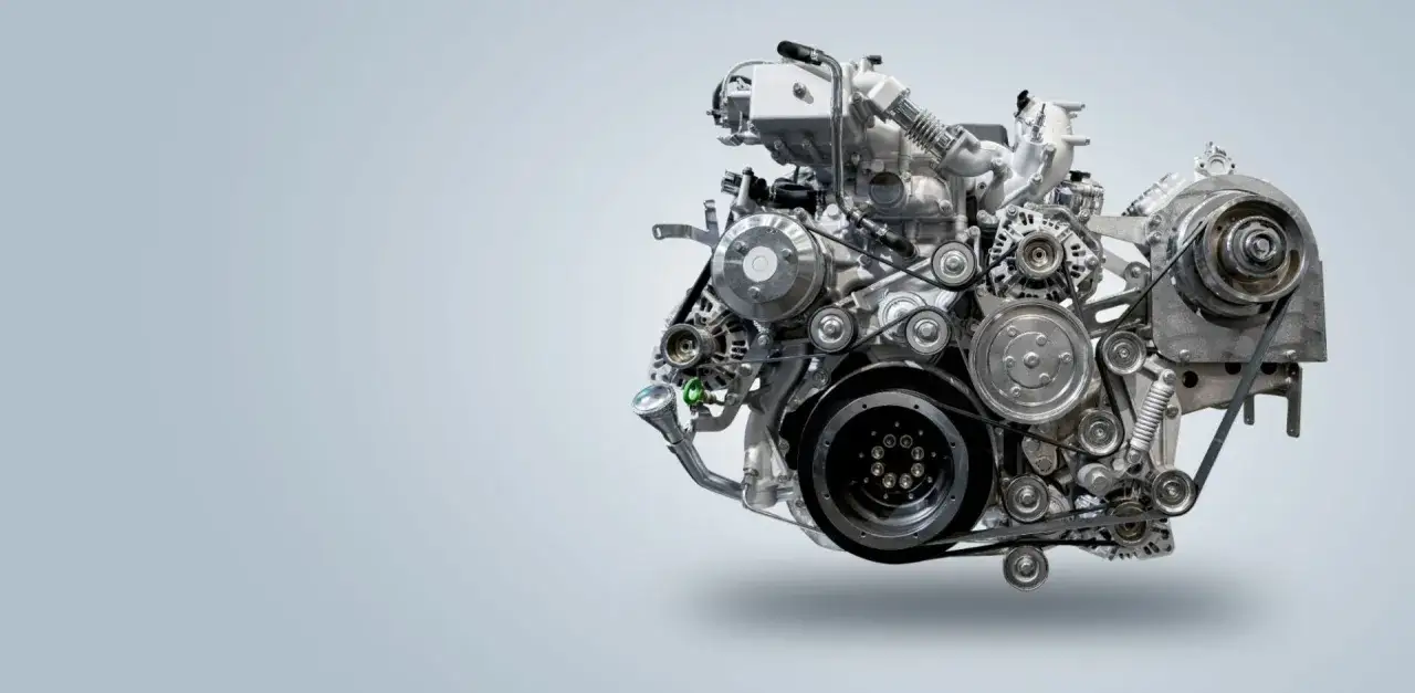 Złożony mechanizm silnika, serce wielu aut spalinowych, z licznymi paskami i kołami pasowymi.