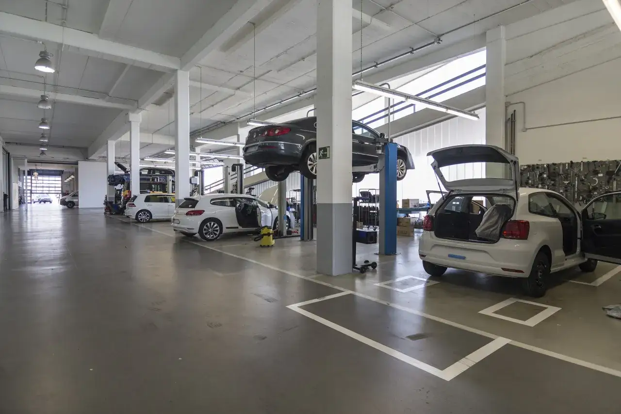 Warsztat samochodowy z kilkoma autami marki VW na podnośnikach i na podłodze, gotowymi do akcje serwisowe vw.