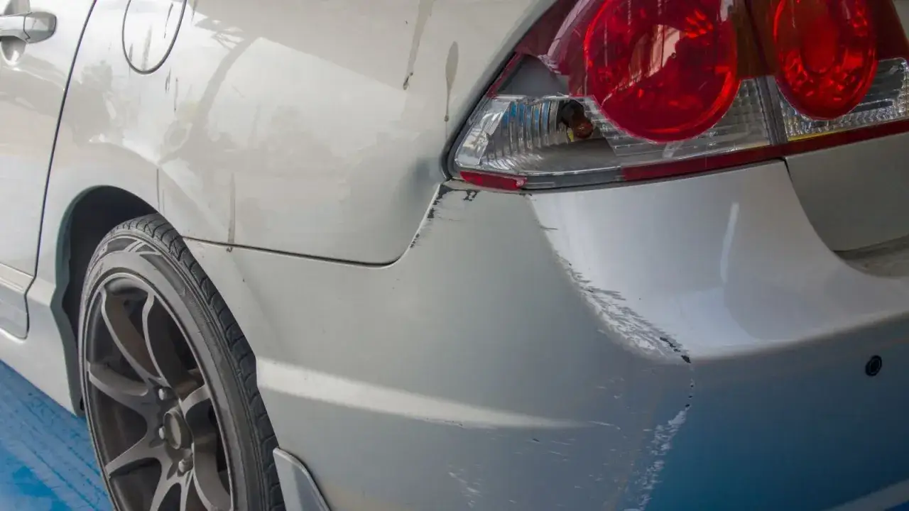 Uszkodzony tył samochodu po parkingowej stłuczce. Wgniecenie i liczne zarysowania lakieru. Taka szkoda może wpłynąć na wartość auta w leasingu.