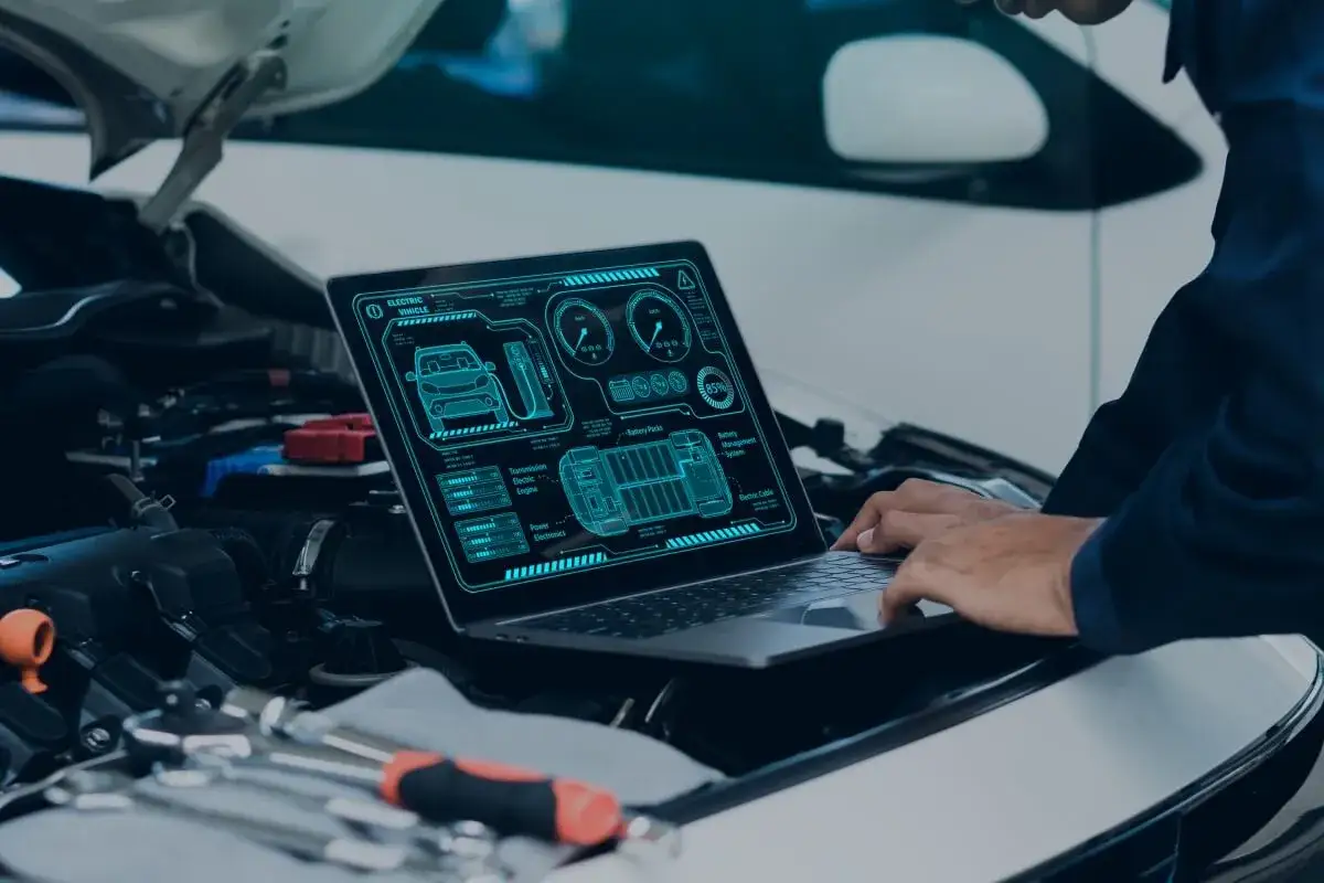 Mechanik diagnozuje problem z elektrycznym autem, które nagle gaśnie podczas jazdy, analizując dane na ekranie laptopa.