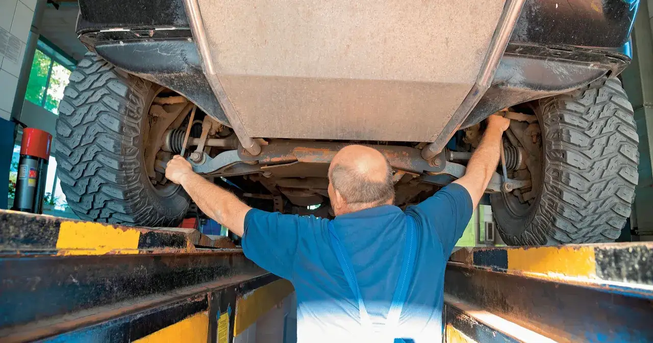 Mechanik sprawdza zawieszenie, szukając przyczyny stukania w kole.