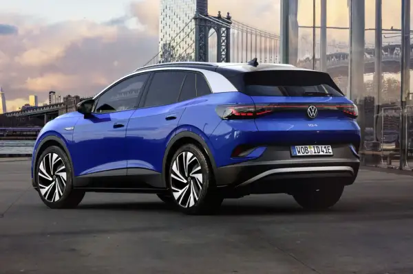 Niebieski VW ID.4 z imponującym zasięgiem, zaparkowany na tle miejskiego krajobrazu z mostem w tle.