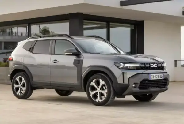 Szary Dacia Duster, jeden z najlepszych aut do gazu, parkuje przed nowoczesnym budynkiem.