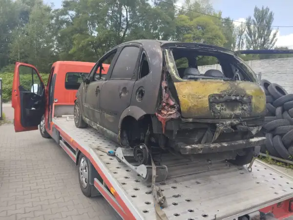 Spalony samochód na lawecie, gotowy do złomowania. Może to być początek drogi po dopłatę za złomowanie starego samochodu.