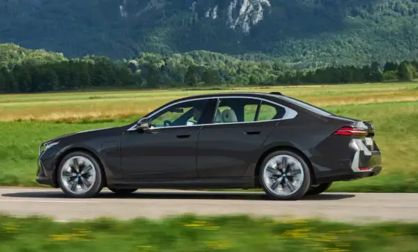 Ciemny sedan BMW jedzie przez malowniczy krajobraz. Idealny do biznesu, gdy rozważasz odliczenie VAT od leasingu samochodu osobowego powyżej 150 tys.