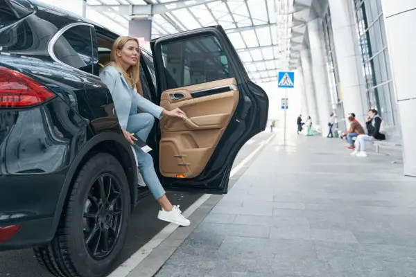 Kobieta wysiada z czarnego SUV-a. Zastanawia się, czy ubezpieczenie samochodu 75 czy 100 w koszty będzie lepsze.