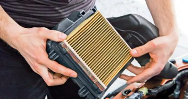 Ręce trzymają nowy filtr powietrza, gotowe do montażu. Dowiedz się, jak wymienić filtr powietrza w swoim samochodzie.