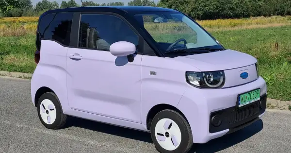 Fioletowy samochód elektryczny na tle łąki. Czy wady samochodów elektrycznych są widoczne w jego kompaktowej budowie?