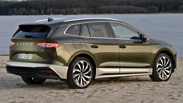 Zielony Skoda Enyaq na plaży, z widokiem na zamarznięte jezioro. Poznaj skoda enyaq wymiary i jego przestronne wnętrze.