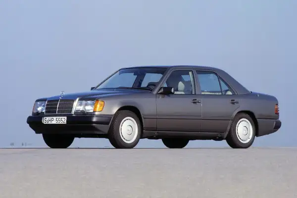 Szary Mercedes W124, symbol najbardziej niezawodnych samochodów, stoi na płaskiej nawierzchni.