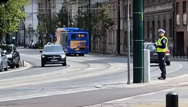 Policjant w kamizelce odblaskowej stoi przy ulicy, kontrolując ruch. Czy radiowóz musi być widoczny, by zapewnić bezpieczeństwo?