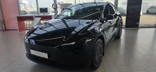Błyszczący, czarny Tesla Model Y, idealny dla siedmioosobowej rodziny, stoi w salonie.