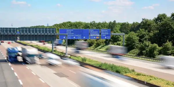 Autostrada w Niemczech, znaki drogowe wskazujące kierunki miast. Uważaj na odsetki za niezapłacony mandat w Niemczech, bo mogą Cię dogonić jak te ciężarówki.