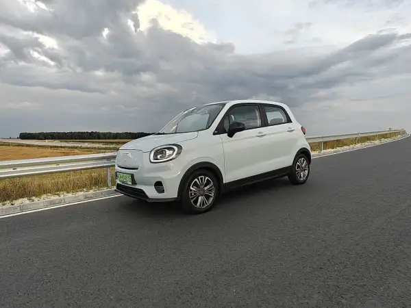 Biały samochód elektryczny na drodze, symbol rosnącej liczby aut elektrycznych w Polsce.