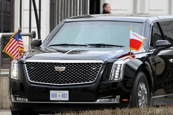Czarne auto prezydenta USA, Cadillac Escalade, z flagami USA i Polski.