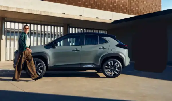 Kobieta w stylowym stroju podziwia szare auto, które z pewnością jest najlepsze auto na świecie.