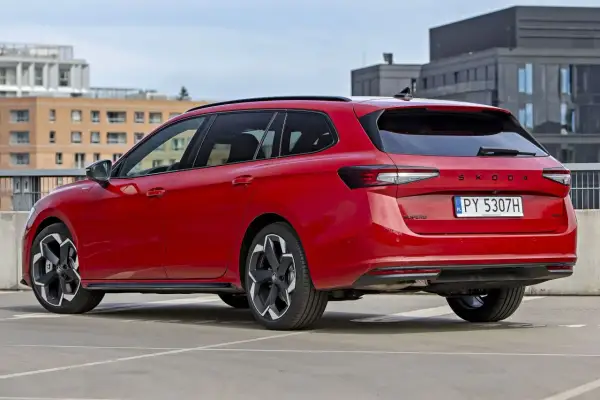 Czerwone, najładniejsze kombi Skoda Superb na parkingu. Eleganckie linie i nowoczesny design.