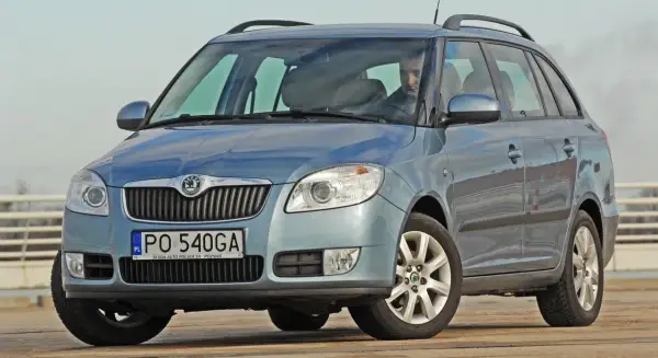 Niebieska Skoda Fabia Combi, idealne jakie auto rodzinne, z kierowcą za kierownicą, na tle jasnego nieba.