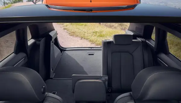 Widok z bagażnika na tylne siedzenia i otwartą klapę. Wnętrze Audi Q3 gotowe na podróż.