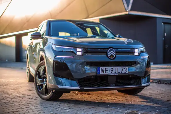 Nowoczesny, ciemnoszary francuski samochód z charakterystycznym logo Citroëna na masce, zaparkowany na brukowanej nawierzchni.