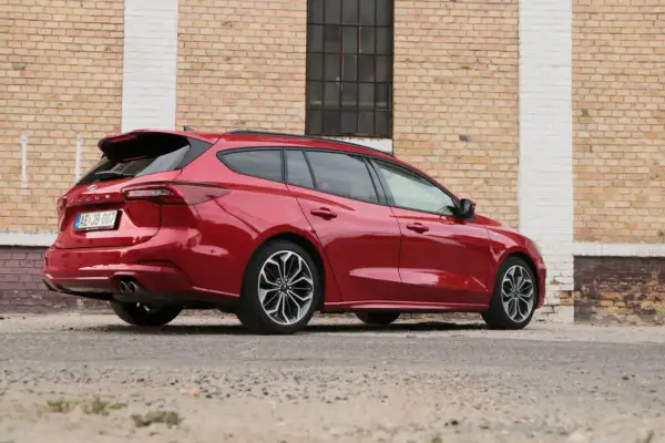Czerwony kombi Ford Focus, elegancki i sportowy, zaparkowany przy ceglanej ścianie.