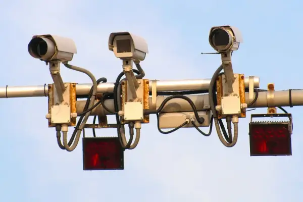Trzy kamery monitorujące ruch drogowy, każda z migającym **system red light** pod nią.