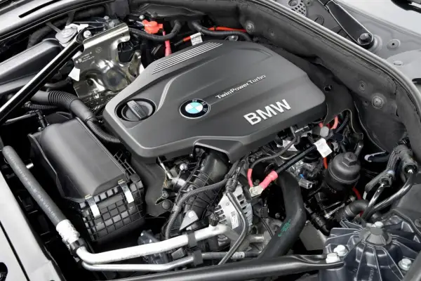 Silniki BMW F10 TwinPower Turbo. Widok na czarny, nowoczesny silnik z logo BMW i licznymi przewodami.