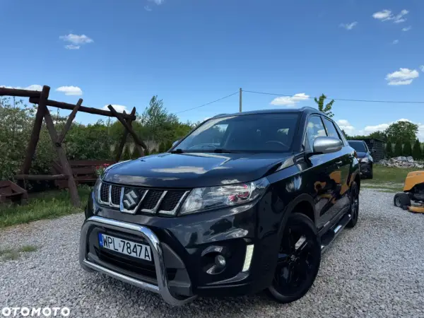 Czarny Suzuki Vitara 1.4 Boosterjet, z chromowanym grillem i zderzakiem, stoi na żwirze. Czyżby awarie?