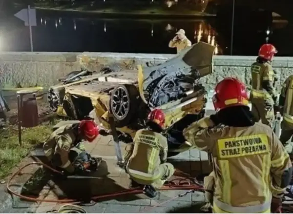 Strażacy pracują przy wraku żółtego samochodu po wypadku Patryka Peretti. Auto jest mocno zniszczone, leży na boku.